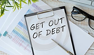 card with text get out of debt against the background of a notebook next to a calculator, reports