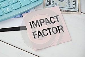 Card with text IMPACT FACTOR on white background, near office supplies and alarm clock.