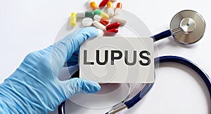 Card with text LUPUS supplies, pills and stethoscope. Medical concept