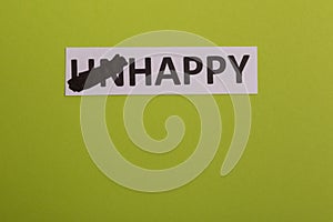 card with text unhappy, erease word & x27;un& x27; so it written & x27;happy& x27;. Copy space. Lime background. Studio shoot photo