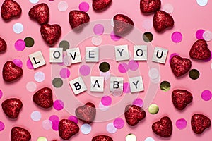 card for valentine's day. on a pink background wooden letters lined with I love you baby. funny congratulations. Flat