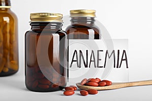 Card with word Anaemia and pills on light background