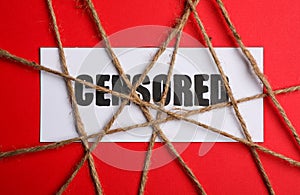 Card with word Censored and twines on red background, flat lay photo
