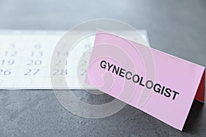 Card with word Gynecologist near calendar on table