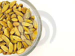 Cardamom pods in glass bowl half of the screen, white background