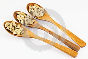 Cardamon pods in three wooden spoons.