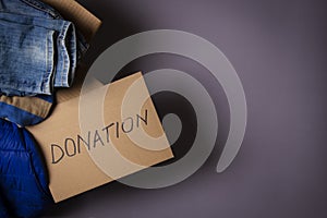 Cardboard box with clothes and card with inscription Donation on gray background. Clothing for donation, charity. Top