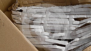 Cardboard box full of cut packaging paper material for parcel protection.