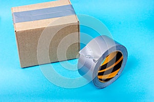 Cardboard box sealed with adhesive tape and gray adhesive tape. Packing parcels with adhesive tape.