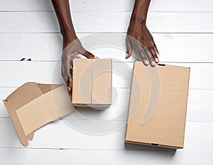 A woman with empty cardboard boxes on a white wooden background. Creating a model