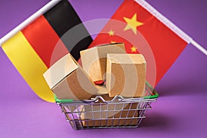 Cardboard boxes in a food basket and flags of China and Germany on a colored background, the concept of trade between countries