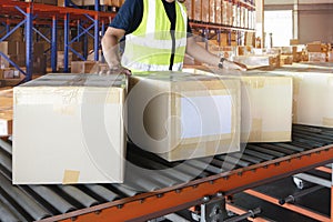 Cardboard boxes sorting on rollers conveyor belt. Worker moving boxes into storage warehouse