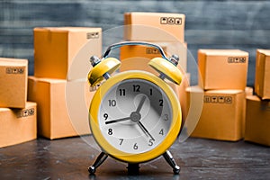 Cardboard boxes and yellow clock. Time of delivery. Limited supply, shortage of goods in stock, hype and consumer fever. Time