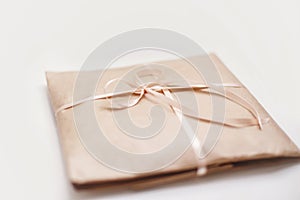 Cardboard carton package wrapped with light brown paper and tied with pink string ribbon in bow