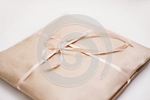 Cardboard carton package wrapped with light brown paper and tied with pink string ribbon in bow