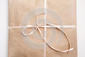 Cardboard carton package wrapped with light brown paper and tied with pink string ribbon in bow