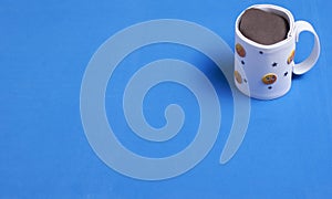 Cardboard cup with chocolate on blue background