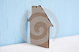 Cardboard cutout house leaned against the wall on blue background