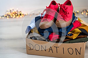 Cardboard donation box full with used clothes and shoes.