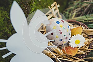 Cardboard Easter bunny looks at Easter egg