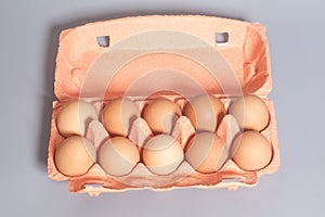 Cardboard egg box with brown eggs on gray