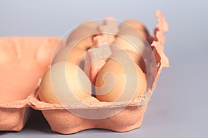 Cardboard egg box with brown eggs on gray