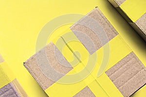 Cardboard package boxes sealed with yellow tape on yellow background. Delivery, shipment, packing concept