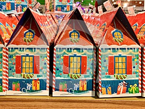 Cardboard packaging of sweets in the shape of a house. Holiday gifts for children. A lot of sweets in beautiful boxes