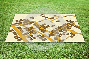 Cardboard sign placed on the ground with an immaginary city map over a green grass