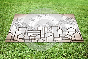 Cardboard sign placed on the ground with an immaginary city map over a green grass
