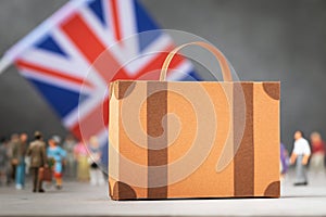Cardboard suitcase, plastic toy people and a flag on an abstract background, a concept on the theme of moving or immigrating to