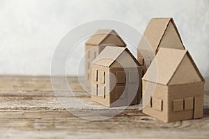 Cardboard toy houses on wooden background. Sale or rental of housing. Neighbors in house. Comfortable life in suburbs