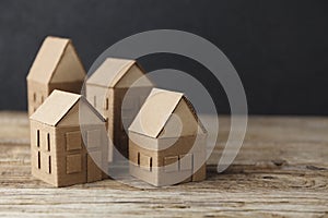 Cardboard toy houses on wooden background. Sale or rental of housing. Neighbors in house. Comfortable life in suburbs