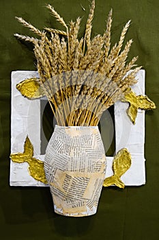Cardboard vase from newspapers, in vase of wheat. A photo frame with fish.