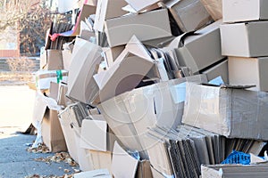 Cardboard and waste paper is collected and packaged for recycling in city in sunny day. Pile of cardboard