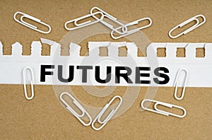 On cardboard, white paper clips and a sheet from a notebook with the inscription - FUTURES