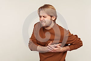 Cardiac health problems. Portrait of man in sweatshirt having sudden painful spasm in chest, suffering heart attack