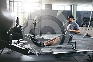 Cardio Training. Sports Man Exercising On Rowing Machine At Gym