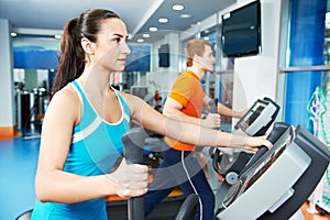 Cardio training. Woman and man at cross-trainers in gym