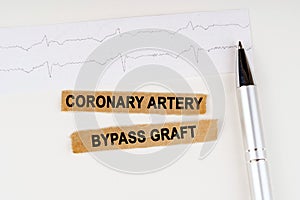On the cardiogram lies a pen and torn paper with the text - Coronary artery bypass graft