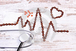 Cardiogram line of coffee grains, stethoscope and supplement pills