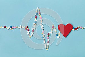 Cardiogram is made of colorful drug pills and red paper heart, pharmaceutical and cardiology concept photo