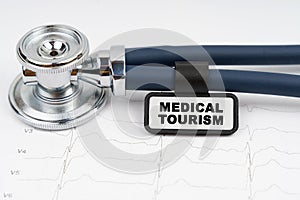 On the cardiogram is a stethoscope and a plate with the inscription - MEDICAL TOURISM