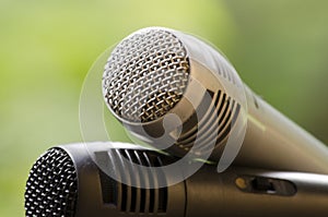 cardioid gray and black microphones on wooden railing with natural background