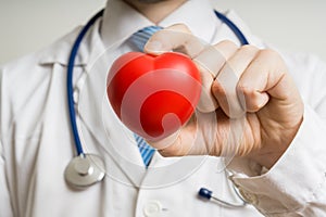 Cardiologist doctor is showing red plastic heart photo