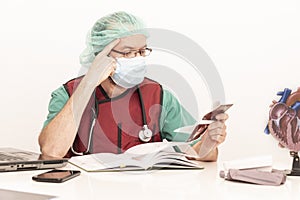 Cardiologist doctor working in his office wearing an operating theatre suit and lead x-ray protective equipment, white background