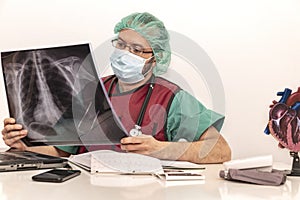 Cardiologist doctor working in his office wearing an operating theatre suit and lead x-ray protective equipment, white background