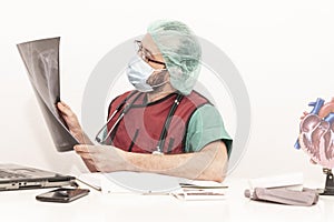 Cardiologist doctor working in his office wearing an operating theatre suit and lead x-ray protective equipment, white background