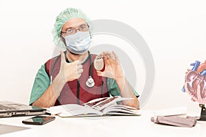 Cardiologist doctor working in his office wearing an operating theatre suit and lead x-ray protective equipment, white background