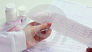 Cardiologist studying patient's heart activity, examining electrocardiogram, EKG